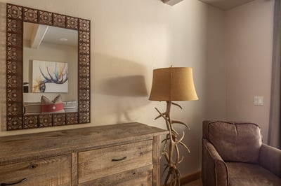 Cozy up in this rustic-chic bedroom corner where warm woods and antler-inspired touches create your 