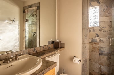 Step into your private spa-like bathroom featuring natural stone tiles and a spacious glass-enclosed