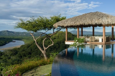 Infinity pool beside an open air palapa overlooking a winding river.