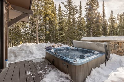 Soak in your private hot tub surrounded by snow-covered pines and golden winter sunlight filtering t