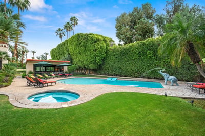 Sprawling backyard oasis featuring a sparkling pool, bubbling hot tub, and lush lawn surrounded by m