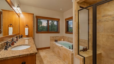 Primary ensuite on main level with tub, shower, and his/her sinks