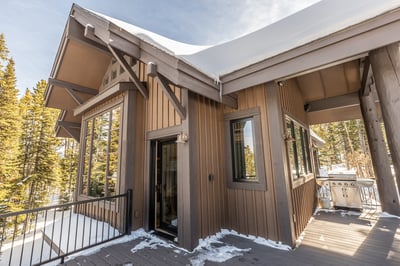 A contemporary mountain lodge featuring warm wood siding and snow-dusted rooflines, nestled among to