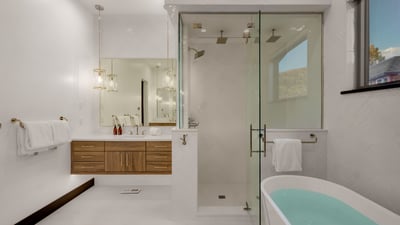 Primary ensuite with separate vanities and 3-head shower