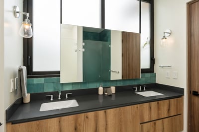 - Get ready with ease at a double sink vanity surrounded by rich wood textures
- Teal tiles and matt