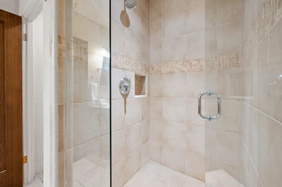 Sleek glass doors and soft neutral tiling create a tranquil space where you can unwind under a refre