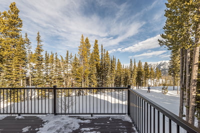 Snow-covered alpine setting with towering evergreens and mountain peaks visible from the property's 
