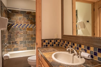 Unwind in your beautifully appointed bathroom, where natural stone tiles and vibrant mosaic accents 