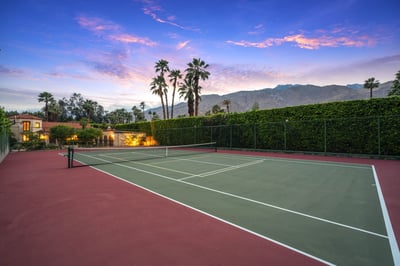 Private tennis court framed by palm trees and mountain views, perfect for an active getaway at this 