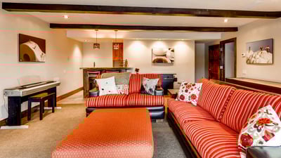 Lower level family room with sofas, TV, fireplace, bar, shuffleboard, arcade game