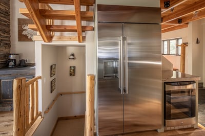Your rustic mountain kitchen features a professional stainless steel refrigerator and warm wood beam