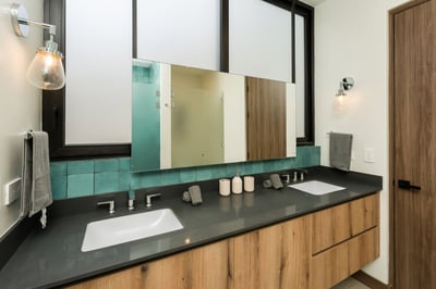 - Bright bathroom with double sinks, plenty of counter space, and warm wood drawers
- Glossy green a