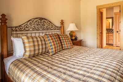 Sink into the plush bed with its elegant wrought-iron headboard, wrapped in soft plaid linens.
