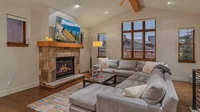 Main level great room with gas fireplace, TV, and deck access