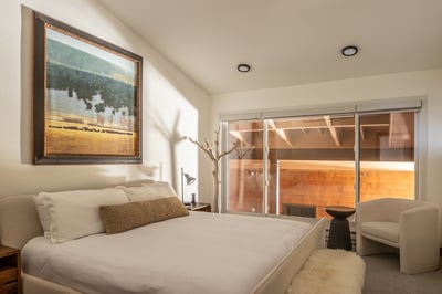Drift off in this serene bedroom where warm light filters through floor-to-ceiling windows, creating