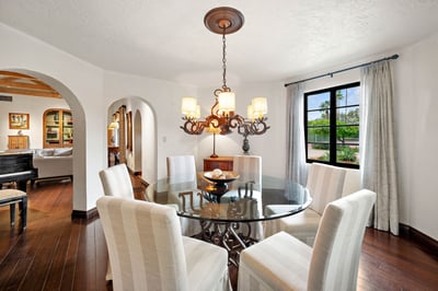 Gather around the elegant glass dining table under a striking chandelier, where warm wood floors and