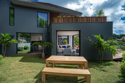Outdoors: Small garden with an outdoor dining room, flanked by a green hillside