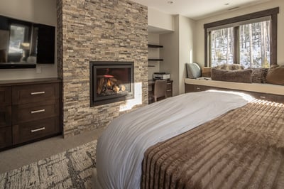 Unwind in your cozy bedroom sanctuary with a crackling fireplace and peaceful forest views from your