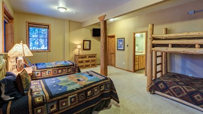 Lower level bedroom with bunk bed and two twin beds, ensuite bathroom
