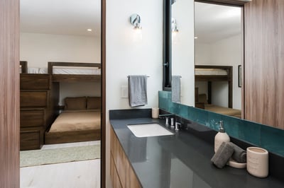 - Functional and connected, this bathroom opens into a cozy bunk sleeping space
- Modern vanity with