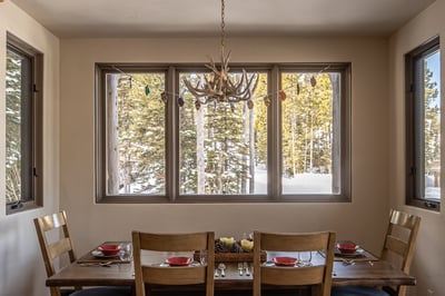 Gather around this rustic dining table where winter forest views create the perfect backdrop for you