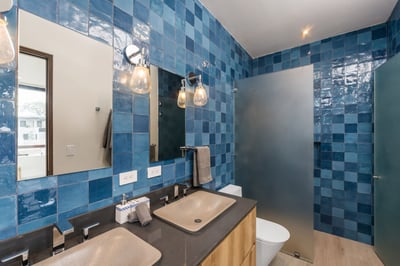 - Vibrant blue tilework surrounds a sleek bathroom featuring dual rectangular sinks
- Frosted glass 