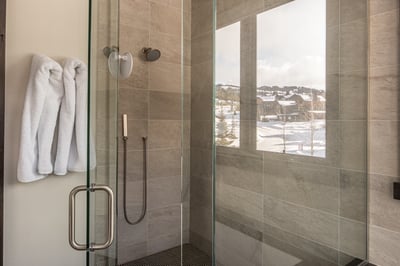 Step into your sleek glass-enclosed shower with pristine tiles and fresh towels ready for your arriv