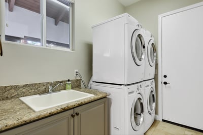 2 washing machines and dryers along with utility sink in laundry room.