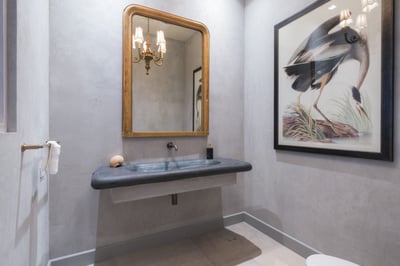 - Textured charcoal basin pairs with warm gold accents and fine lighting
- Artistic touches like the