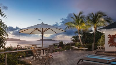 Gazebo: Outside wooden dining table with four chairs surrounded by tropical vegetation.