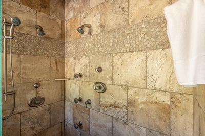 Unwind under dual rainfall showerheads and body jets in your luxurious stone-tiled shower.