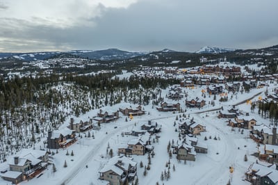 Winter mountain village nestled in snow-covered peaks with cozy alpine homes illuminated against the