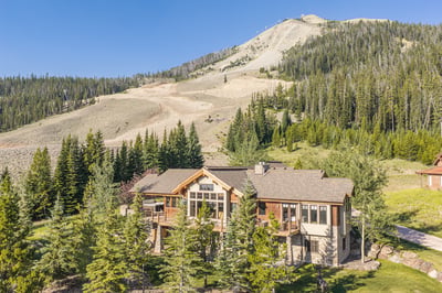 An elevated view captures a beautiful mountain lodge surrounded by towering evergreens.
