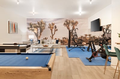 The gym is outfitted with a Peloton Spin Bike and strength equipment while the game room boasts a bi