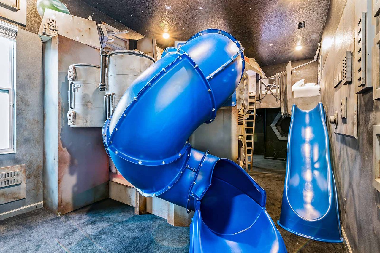 A spaceship-themed kids bunk room with slides inside a large Orlando vacation villa