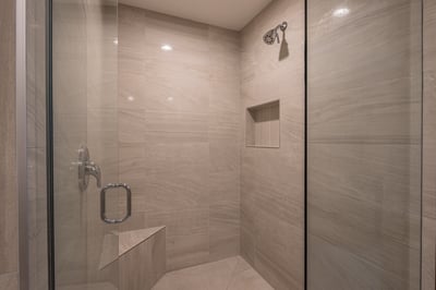 Step into your sleek walk-in shower featuring modern stone tiles, rainfall showerhead, and built-in 