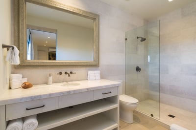 - Refresh in a warm neutral space featuring glass walk in shower and marble sink
- Wide framed mirro