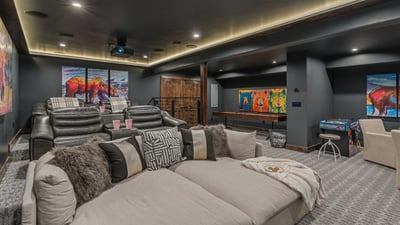 Theater room on lower level with a huge comfy couch, luxury theater seats, and shuffleboard, and arc
