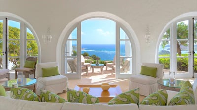 Living Area: Large, high-ceilinged space well-appointed with comfortable off­-white sofas and ar