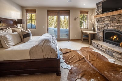 Cozy up in your mountain bedroom where crackling fireplace warmth meets snowy forest views through F