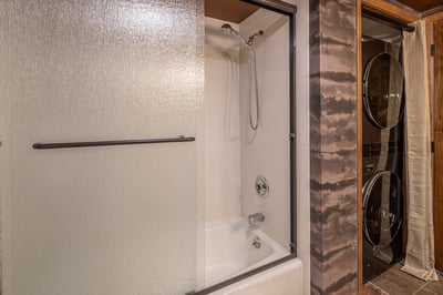 Your private bathroom features a modern tub-shower combo with sleek glass doors, plus convenient in-
