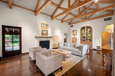 Unwind in your elegant living room with vaulted wood-beam ceilings, plush seating, and a cozy firepl